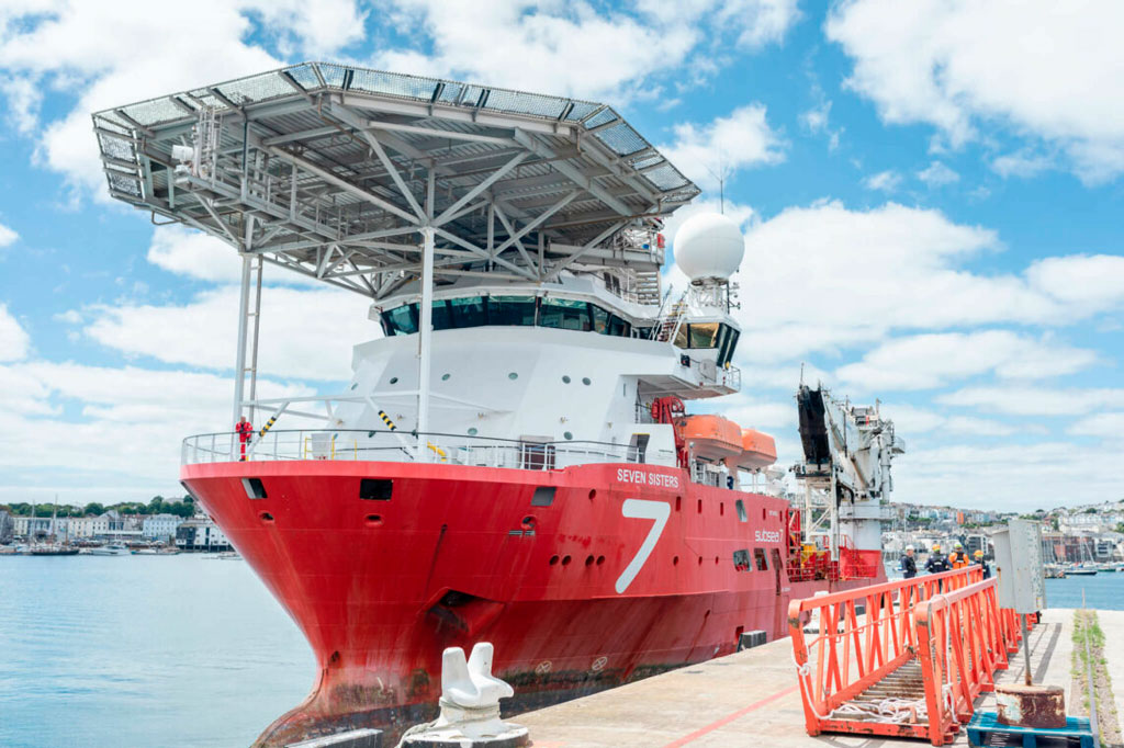 Offshore vessel docked at a port, with helideck and crane equipment.