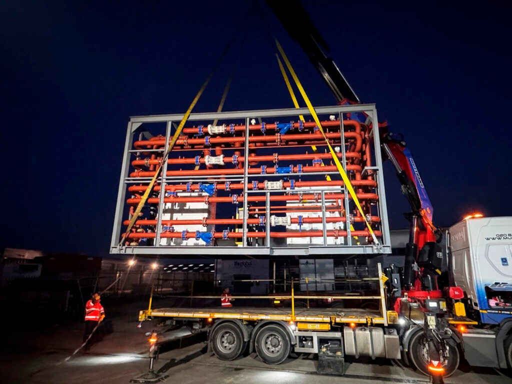 A lorry carrying a secured pipework structure.