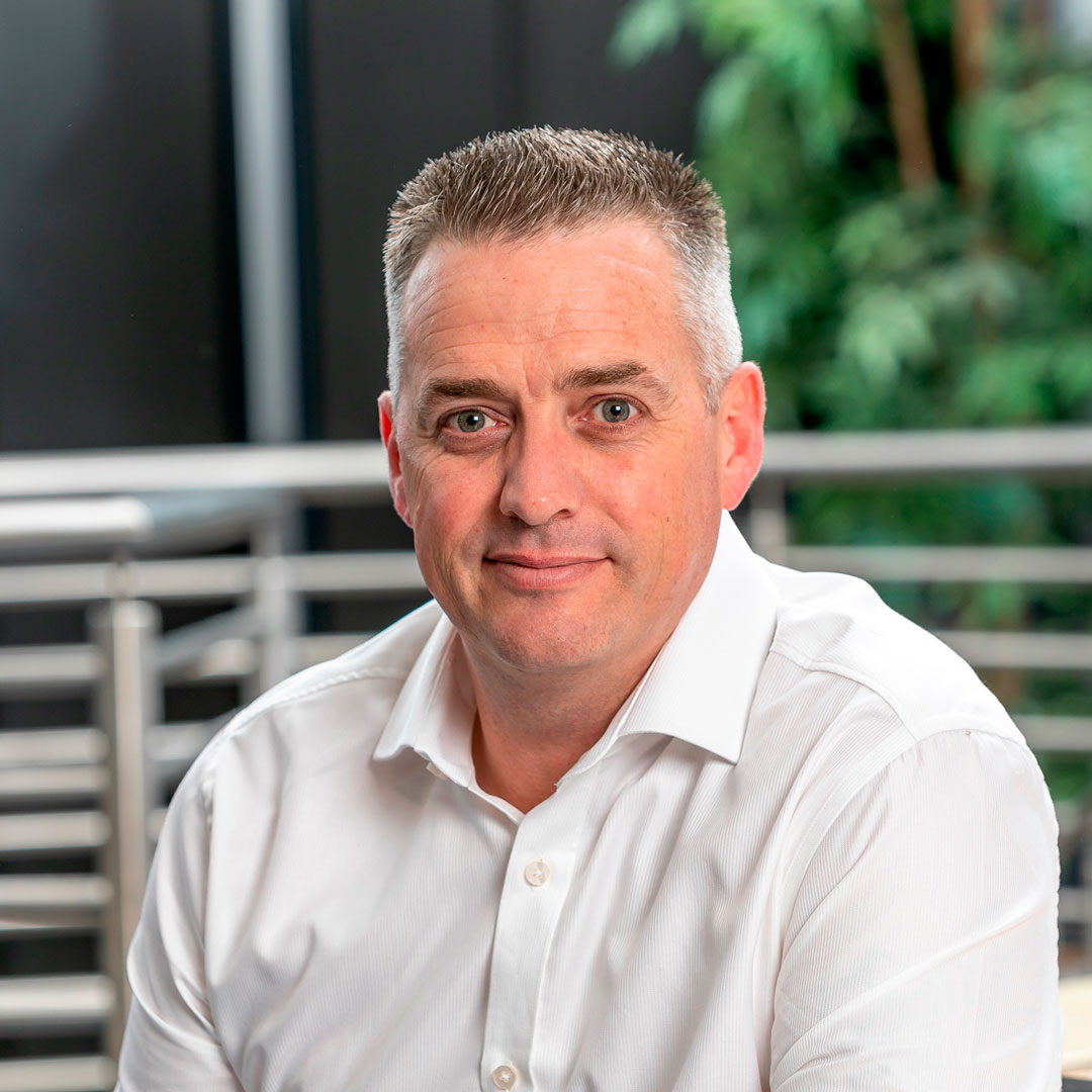 Man with grey hair wearing a white shirt.