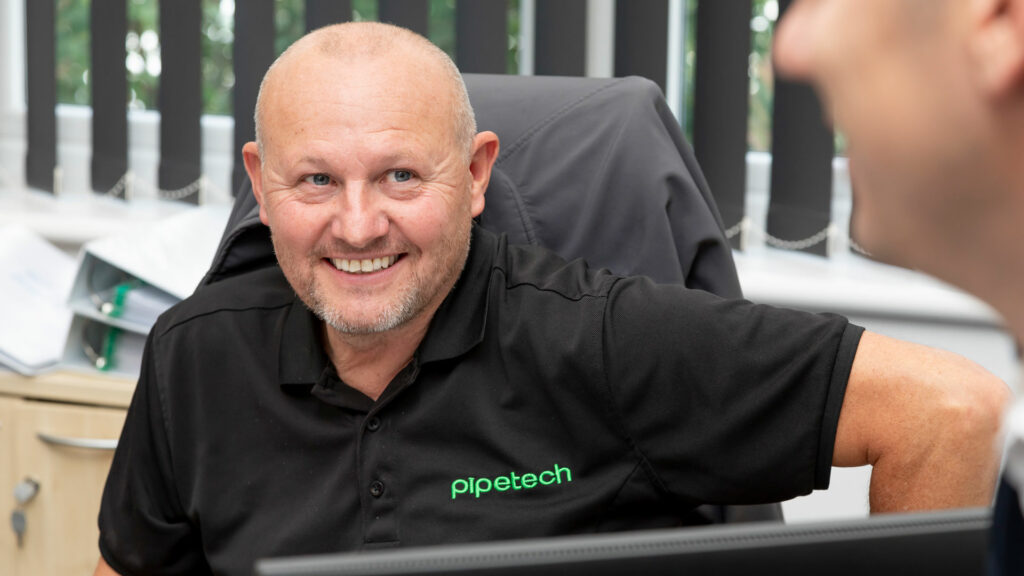 Man sat in an office chair wearing a black branded t-shirt