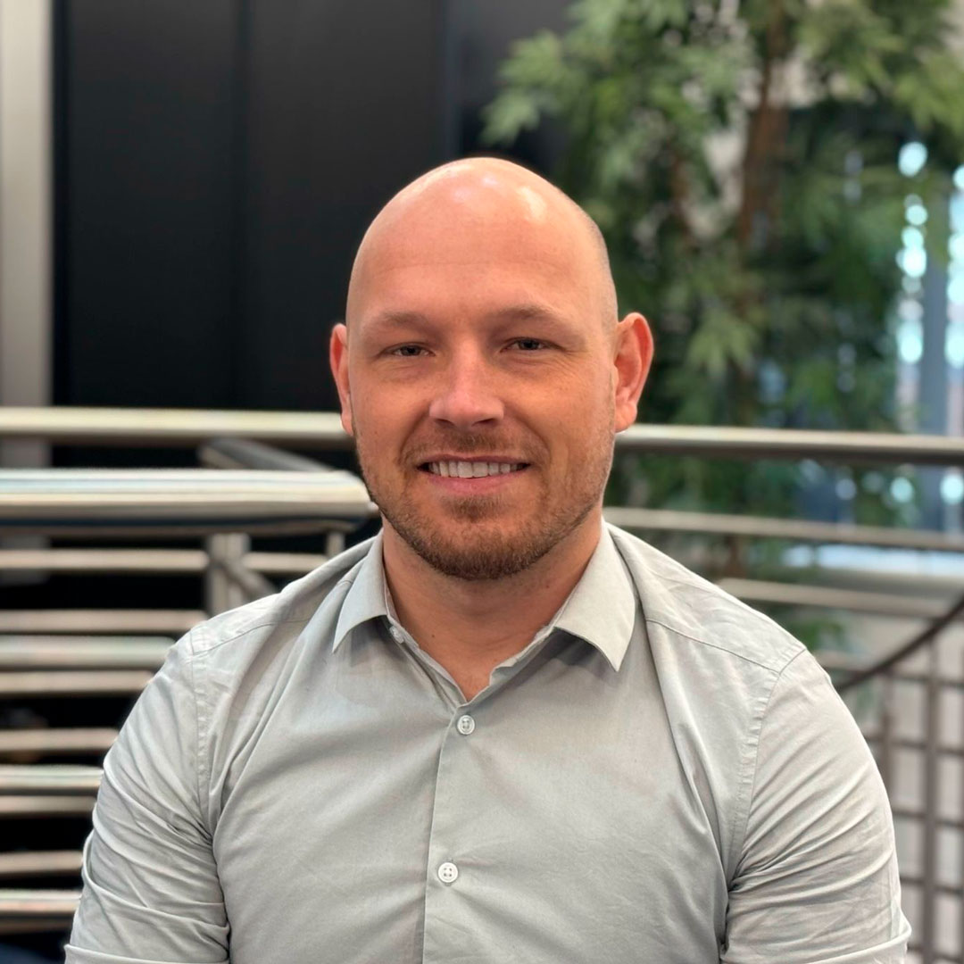 Bald man wearing a grey shirt.