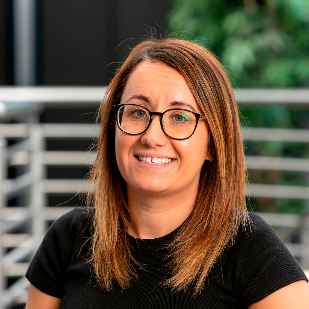 Lady with brown hair wearing glasses and a black t-shirt.